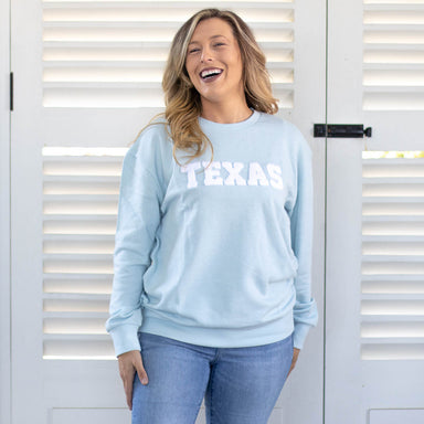light blue, long sleeve crew neck sweatshirt with the word TEXAS in white embroidered lettering