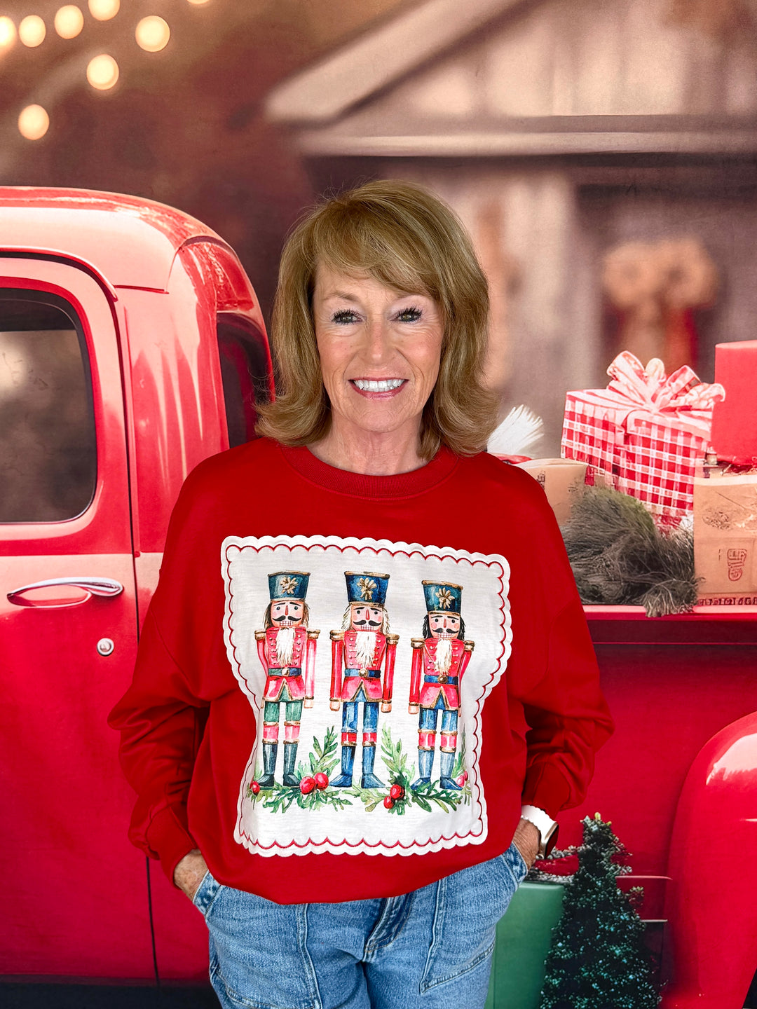 woman in red sweatshirt with trio of nutcrackers sewn on in an applique print with a scalloped border