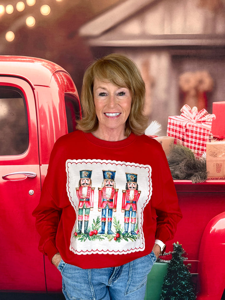woman in red sweatshirt with trio of nutcrackers sewn on in an applique print with a scalloped border