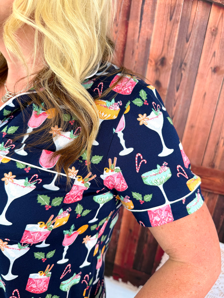 Woman modeling a navy tops and bottoms pajama set with different cocktails in a repeating pattern.