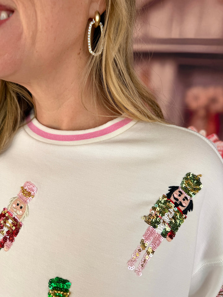 close up of sweatshirt with pink banding on neckline and sequin nutcrackers
