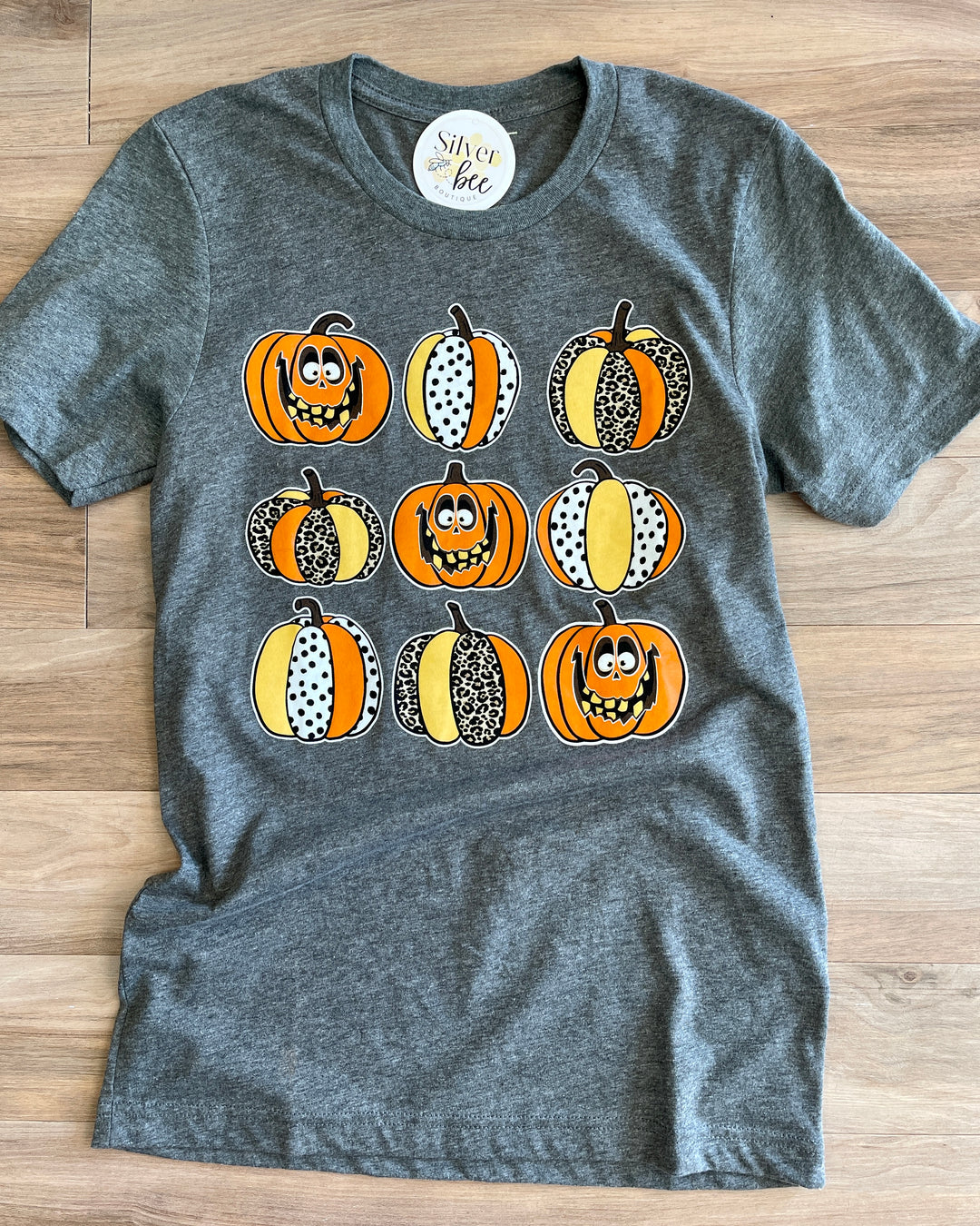 soft grey tee with 9 patterned pumpkins with silly faces