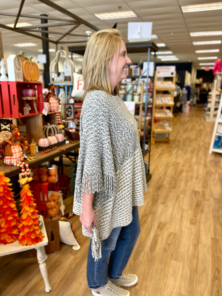 poncho style sweater with cgarcoal and cream striping and fringe at edges