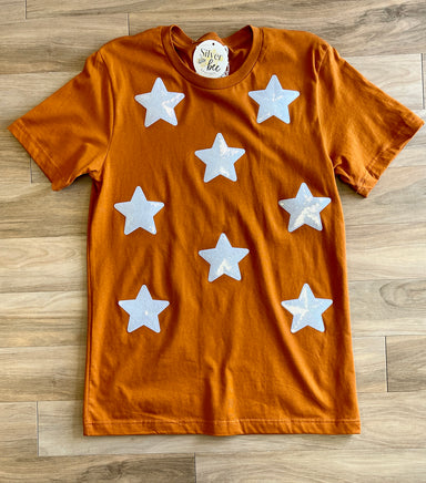 burnt orange tee with white iridescant stars sewn onto front of tee, short sleeve tee