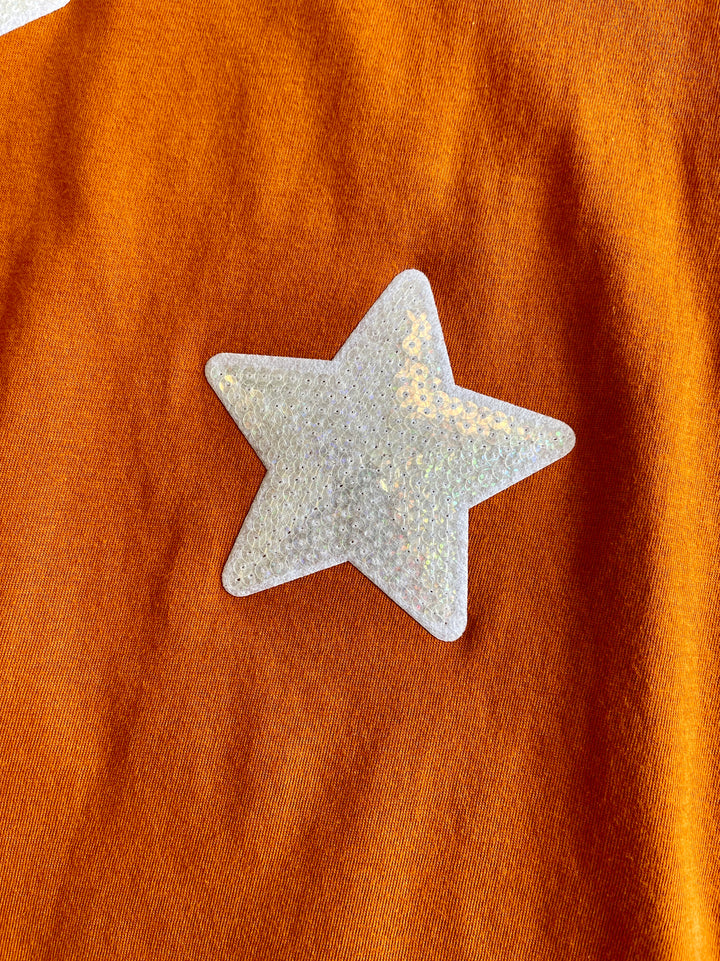 burnt orange tee with white iridescant stars sewn onto front of tee, short sleeve tee