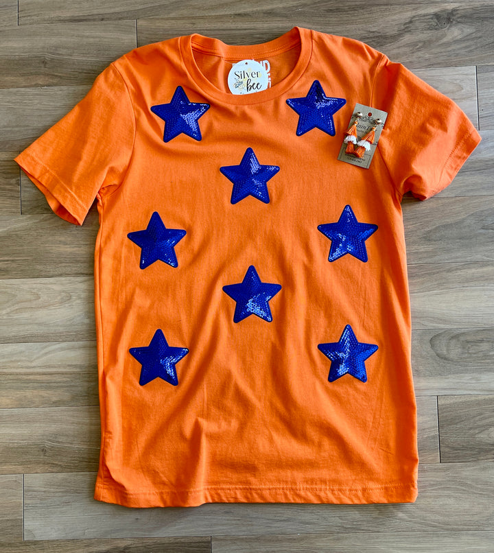 orange tee with royal blue iridescant stars sewn onto front of tee, short sleeve tee