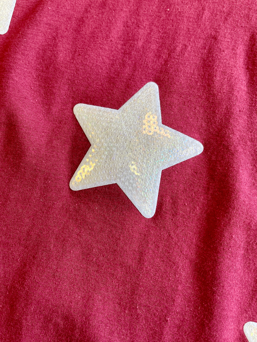 maroon tee with white iridescant stars sewn onto front of tee, short sleeve tee