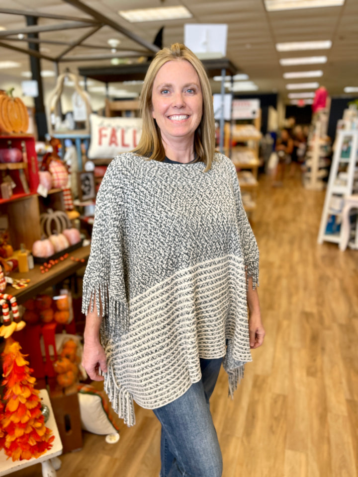 poncho style sweater with charcoal and cream striping and fringe at edges