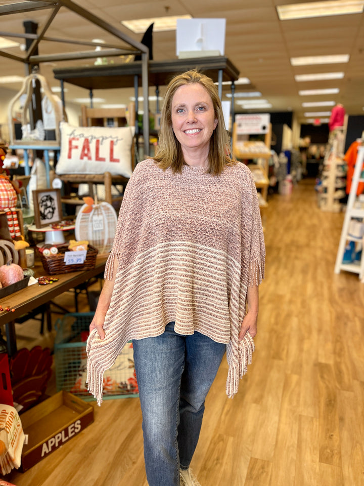 poncho style sweater with pink and cream striping and fringe at edges